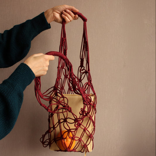 Red woven bag held by a person against a beige background
